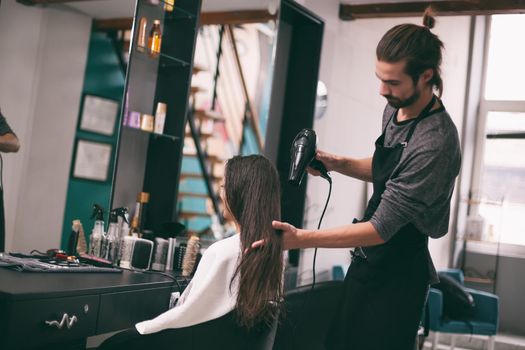 Young woman getting new hairstyle at professional hair styling saloon.