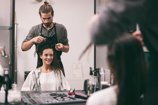 Young woman getting new hairstyle at professional hair styling saloon.