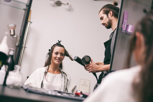 Young woman getting new hairstyle at professional hair styling saloon.