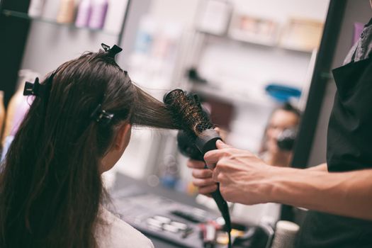 Young woman getting new hairstyle at professional hair styling saloon.