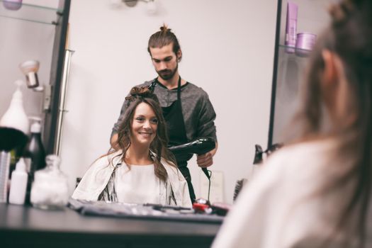 Young woman getting new hairstyle at professional hair styling saloon.