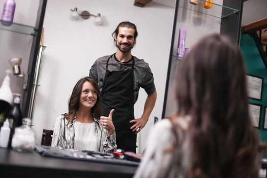 Young woman getting new hairstyle at professional hair styling saloon. She is very satisfied.