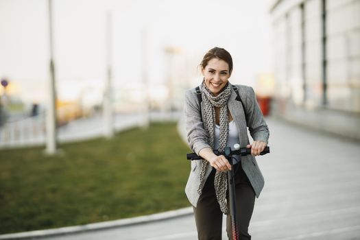 A young businesswoman with an electric push scooter going to work through the city.