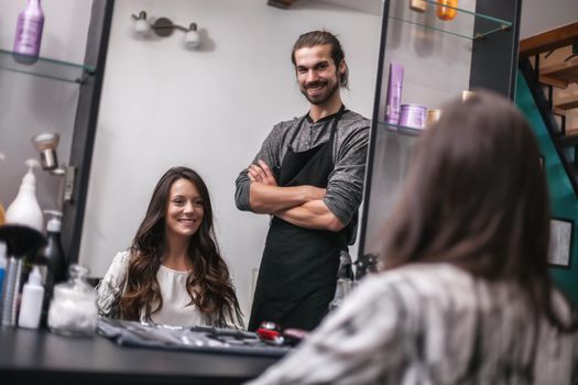 Young woman getting new hairstyle at professional hair styling saloon. She is very satisfied.