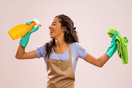 Portrait of african-american housewife who is ready for housework. She is happy and singing.