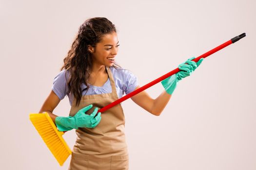 Portrait of happy and successful african-american professional maid having fun with broom.