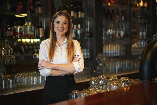 Portrait of happy woman who works as a bartender at bar.