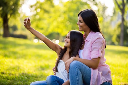 Happy family having nice time in park together. They are taking selfie.