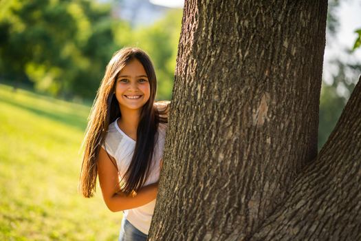Happy little girl is enjoying nature in park.