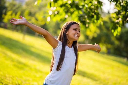 Happy little girl is enjoying nature in park.