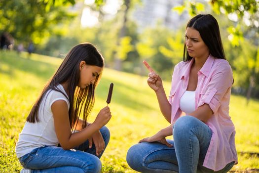 Mother is angry because her daughter is eating too much ice cream.