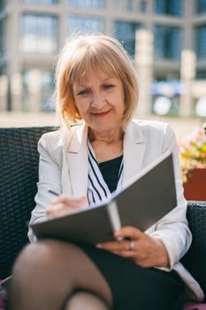 Senior businesswoman is sitting in cafe.