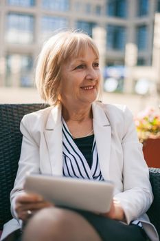 Senior businesswoman is sitting in cafe and searching for job on internet.