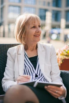 Senior businesswoman is sitting in cafe and making business plans.