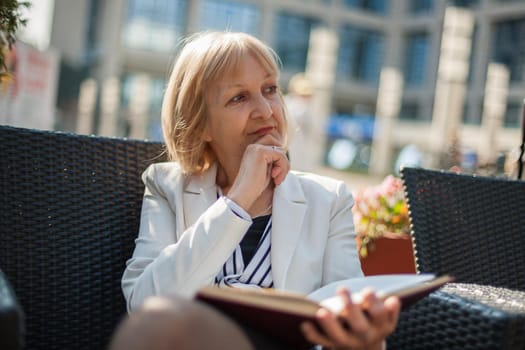 Senior businesswoman is sitting in cafe and making job plans.