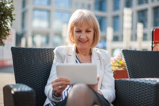 Senior businesswoman is sitting in cafe and searching for job on internet.