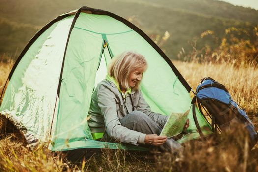 Senior woman is camping in mountain. Active retirement.