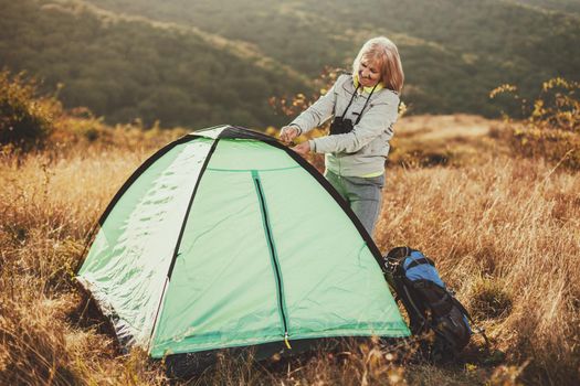 Senior woman is camping in mountain. Active retirement.