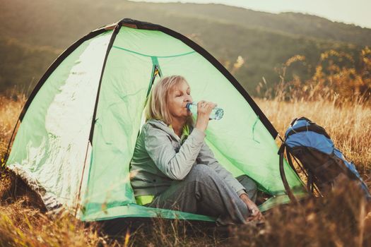 Senior woman is camping in mountain. Active retirement.