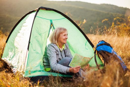 Senior woman is camping in mountain. Active retirement.