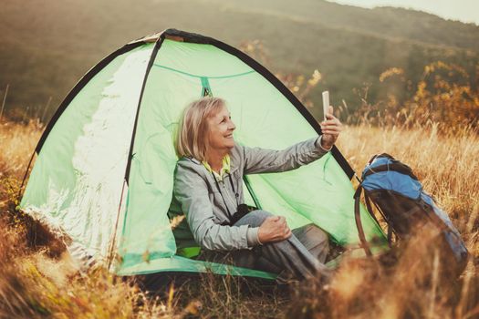 Senior woman is camping in mountain. Active retirement.