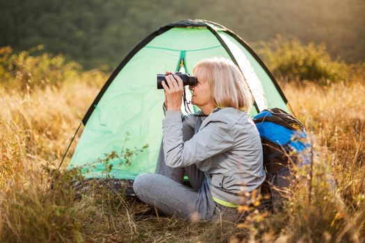 Senior woman is camping in mountain. Active retirement.