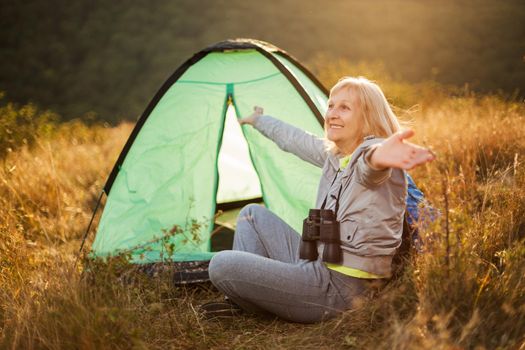 Senior woman is camping in mountain. Active retirement.