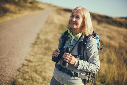 Senior woman is hiking in mountain. Active retirement.
