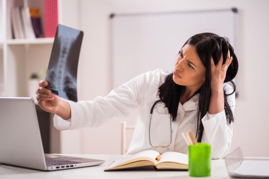 Young doctor is examining x-ray image in her office.