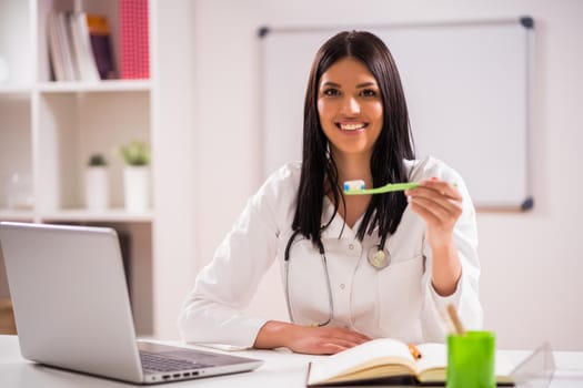 Young doctor is talking about teeth care in her office.