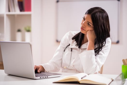 Portrait of tired young female doctor at work.