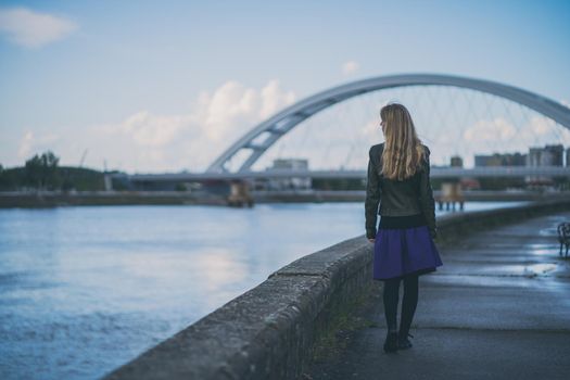 Adult woman walking at quay in the city.