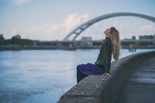 Adult woman relaxing at river bank in the city.