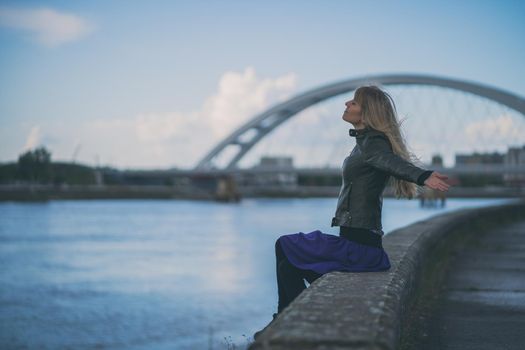 Adult woman relaxing at river bank in the city.