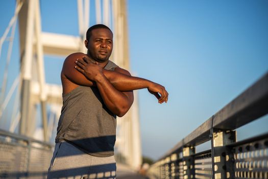 Young african-american man is exercising on the bridge in the city.