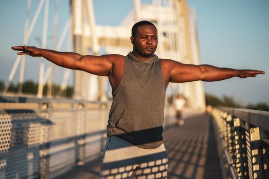 Young african-american man is exercising on the bridge in the city.