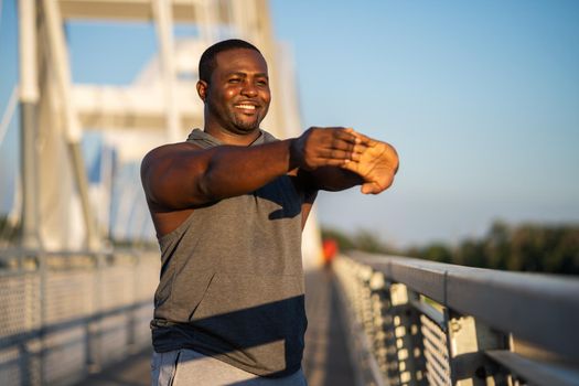 Young african-american man is exercising on the bridge in the city.