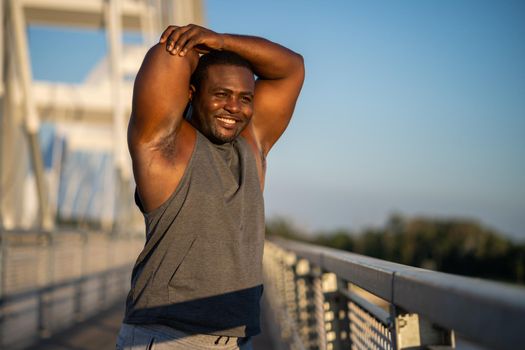 Young african-american man is exercising on the bridge in the city.