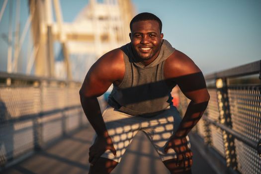 Young african-american man is exercising on the bridge in the city.