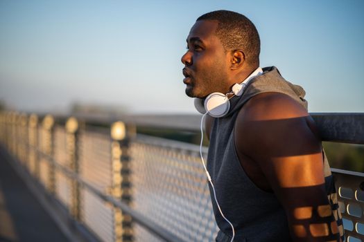 Portrait of young cheerful african-american man in sports clothing who is relaxing after jogging.