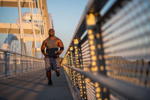 Young african-american man is jogging on the bridge in the city.