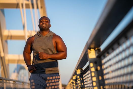 Young african-american man is jogging on the bridge in the city.