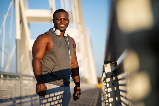 Portrait of young cheerful african-american man in sports clothing who is looking at camera and smiling.