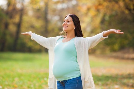 Happy pregnant woman relaxing in park.