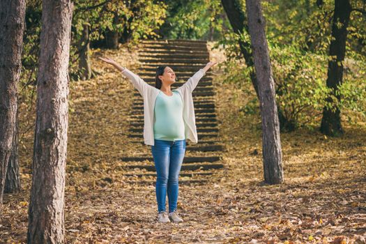 Happy pregnant woman relaxing in park.