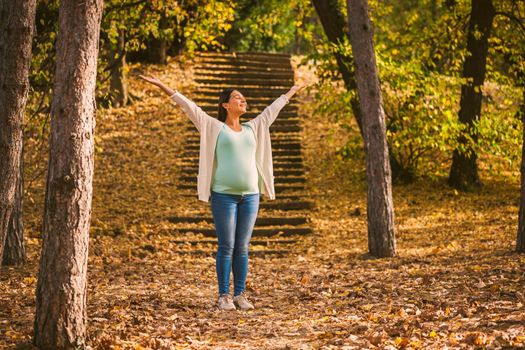 Happy pregnant woman relaxing in park.