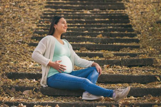 Happy pregnant woman relaxing in park.