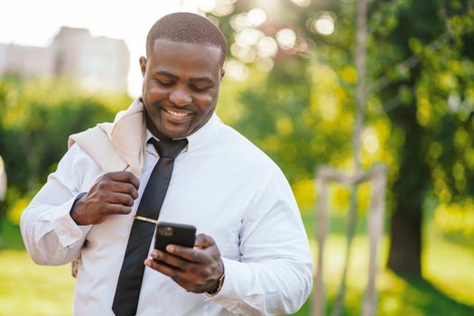 Portrait of happy african-american businessman who is using smartphone.