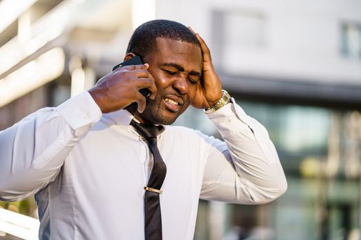 Portrait of frustrated african-american businessman who is using smartphone.