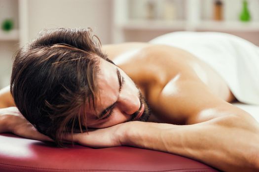 Young man is relaxing after massage on spa treatment.